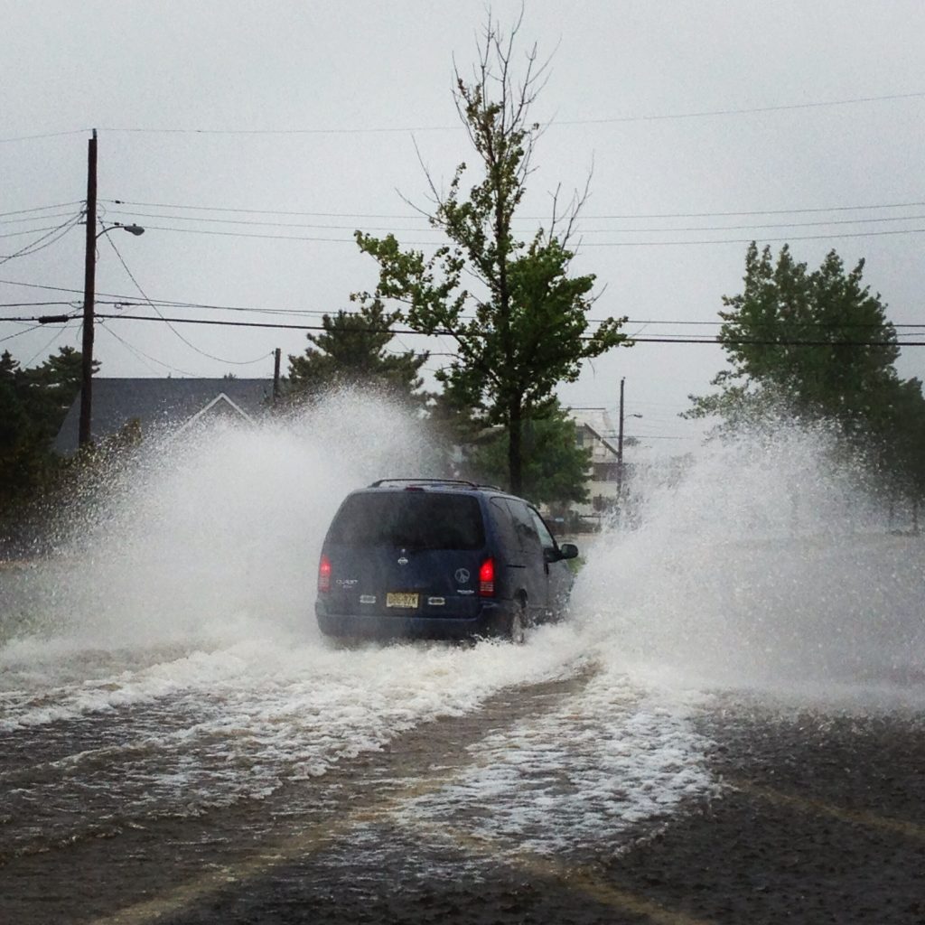 A vehicle speeds down a flooded street in a barrier island community. (Photo: Daniel Nee)