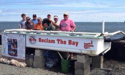 A group of volunteers with 'ReClam the Bay' pose next to an upweller. (Photo: RCTB)